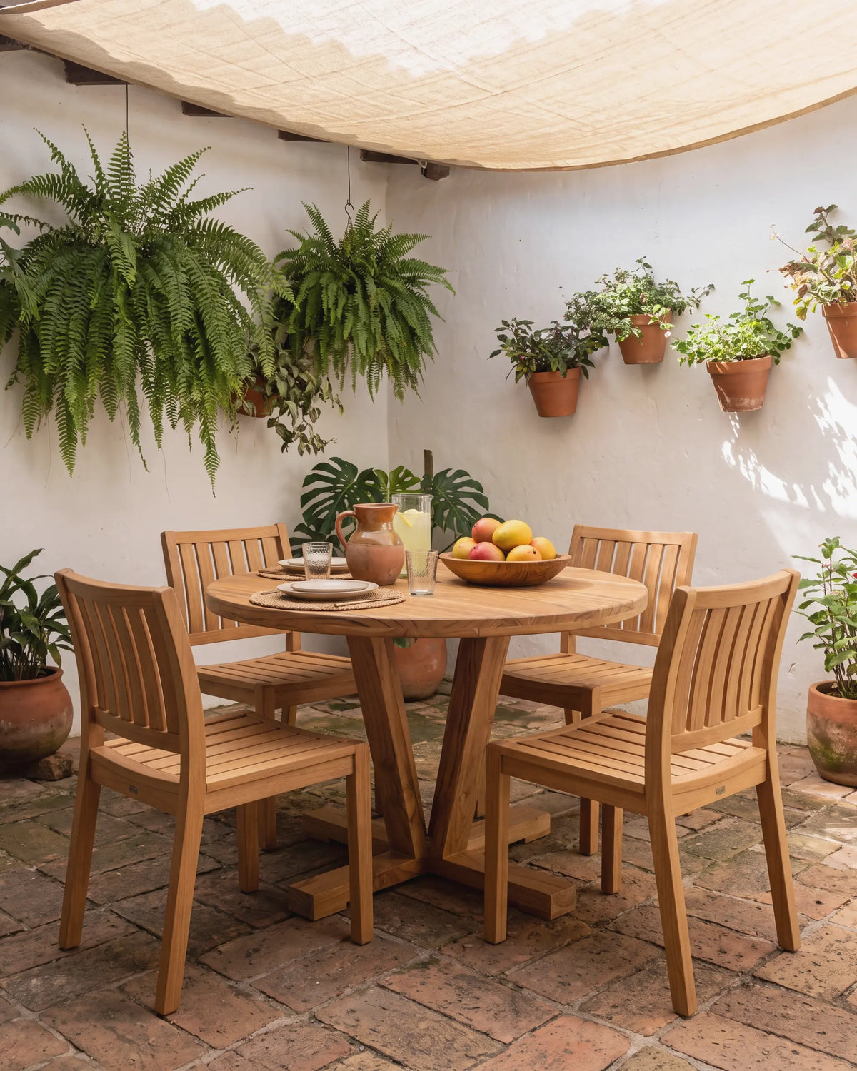 Comedor redondo con sillas de teca en el patio interior de una casa tradicional en Envigado