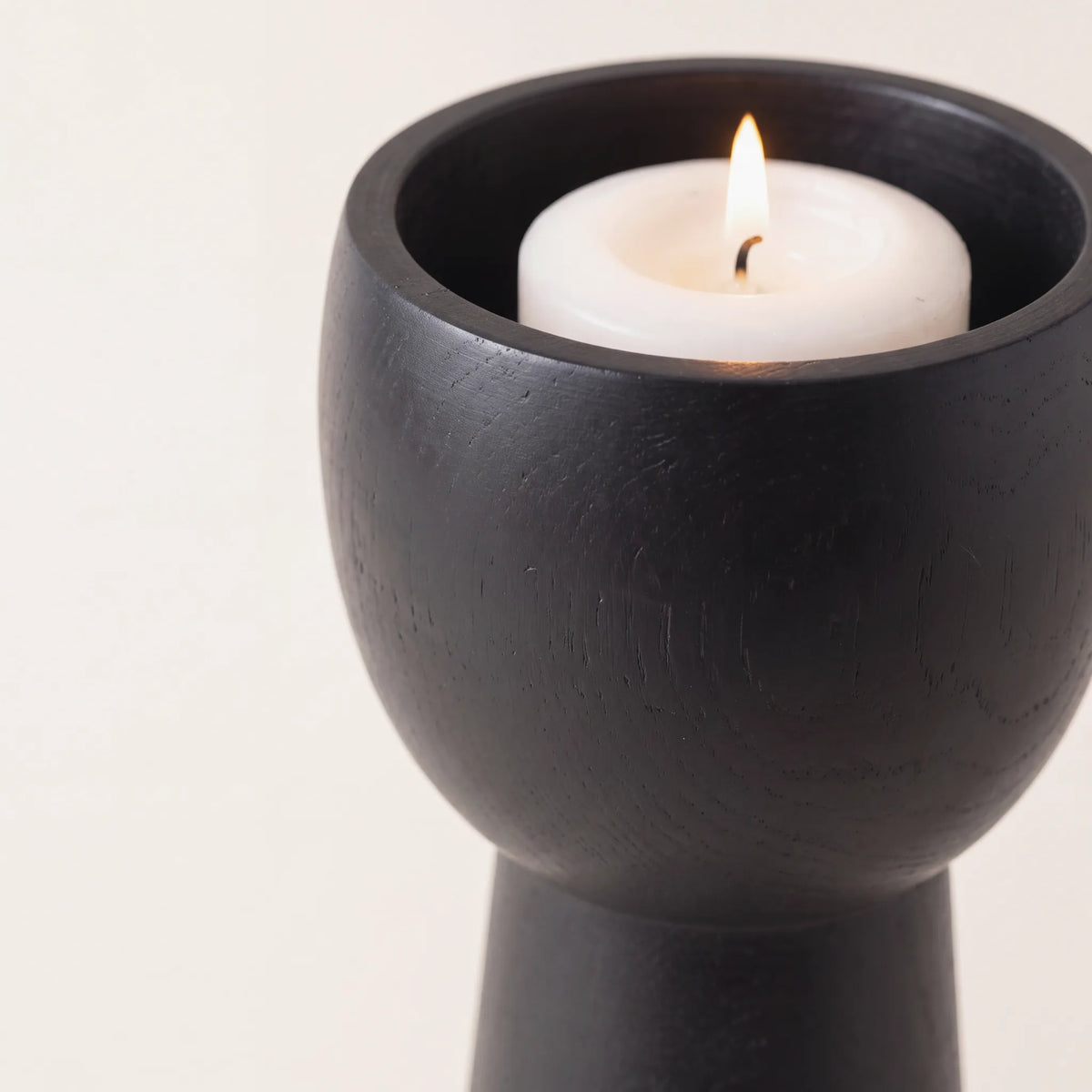 Copa redonda de madera negro mate con vela encendida