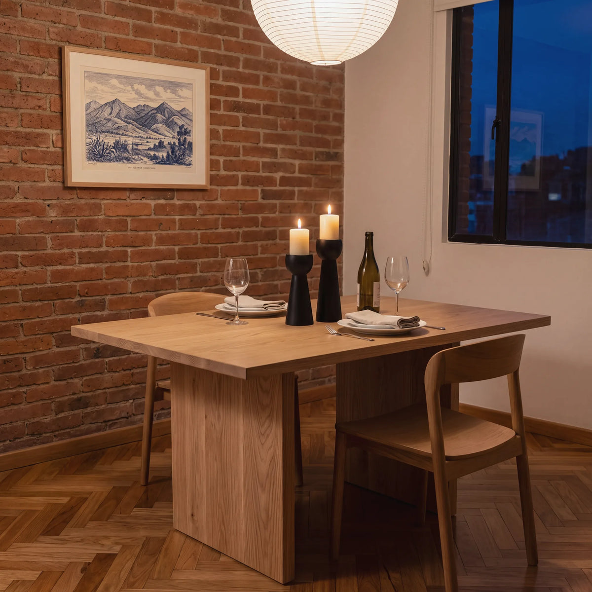 Candelabros negros con velas encendidas sobre una mesa de comedor de roble en un apartamento de Bogotá