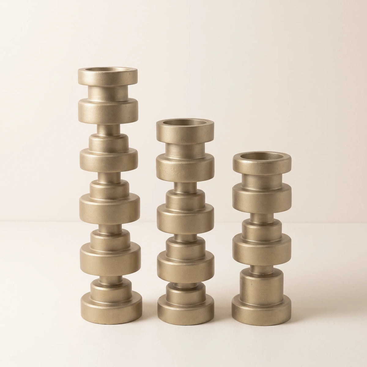 Tres candelabros de discos torneados en acabado dorado de 40, 32 y 24 cm sobre fondo claro