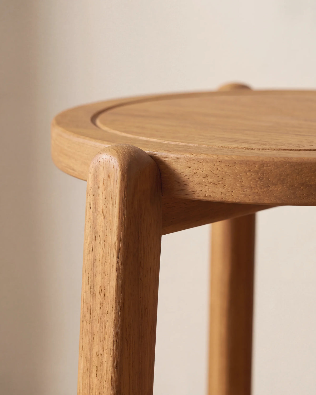 Borde elevado de la tapa redonda y unión con la pata de madera maciza