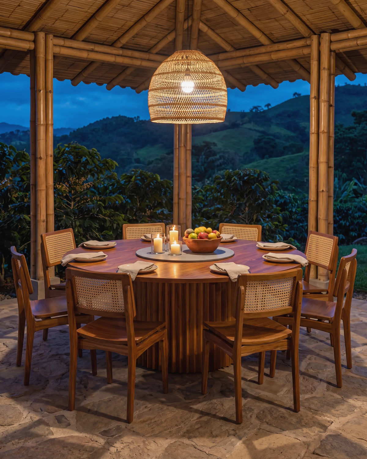 Mesa de comedor redonda de teca servida en un kiosco de guadua de una finca cafetera en Jardín, de noche