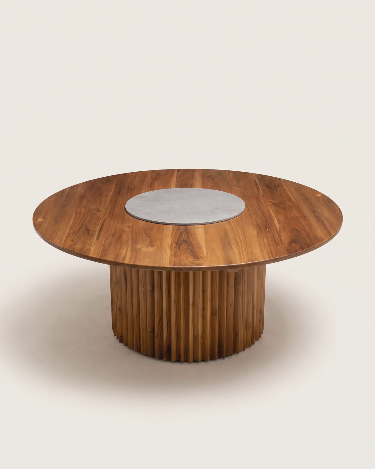 Mesa de comedor redonda de teca con disco de piedra gris embutido al centro sobre fondo claro