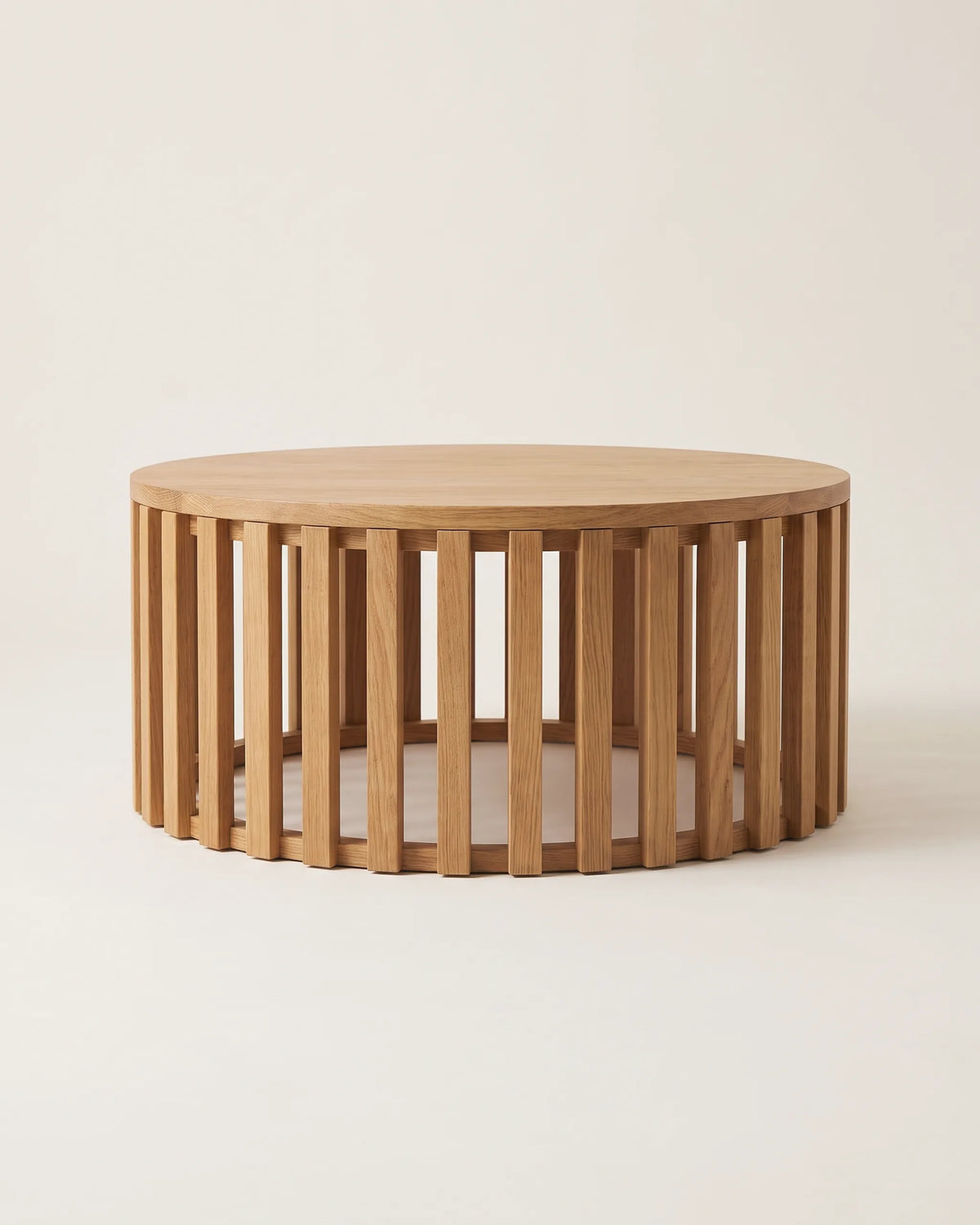 Mesa de centro redonda de roble de 80 cm con base de listones verticales sobre fondo claro