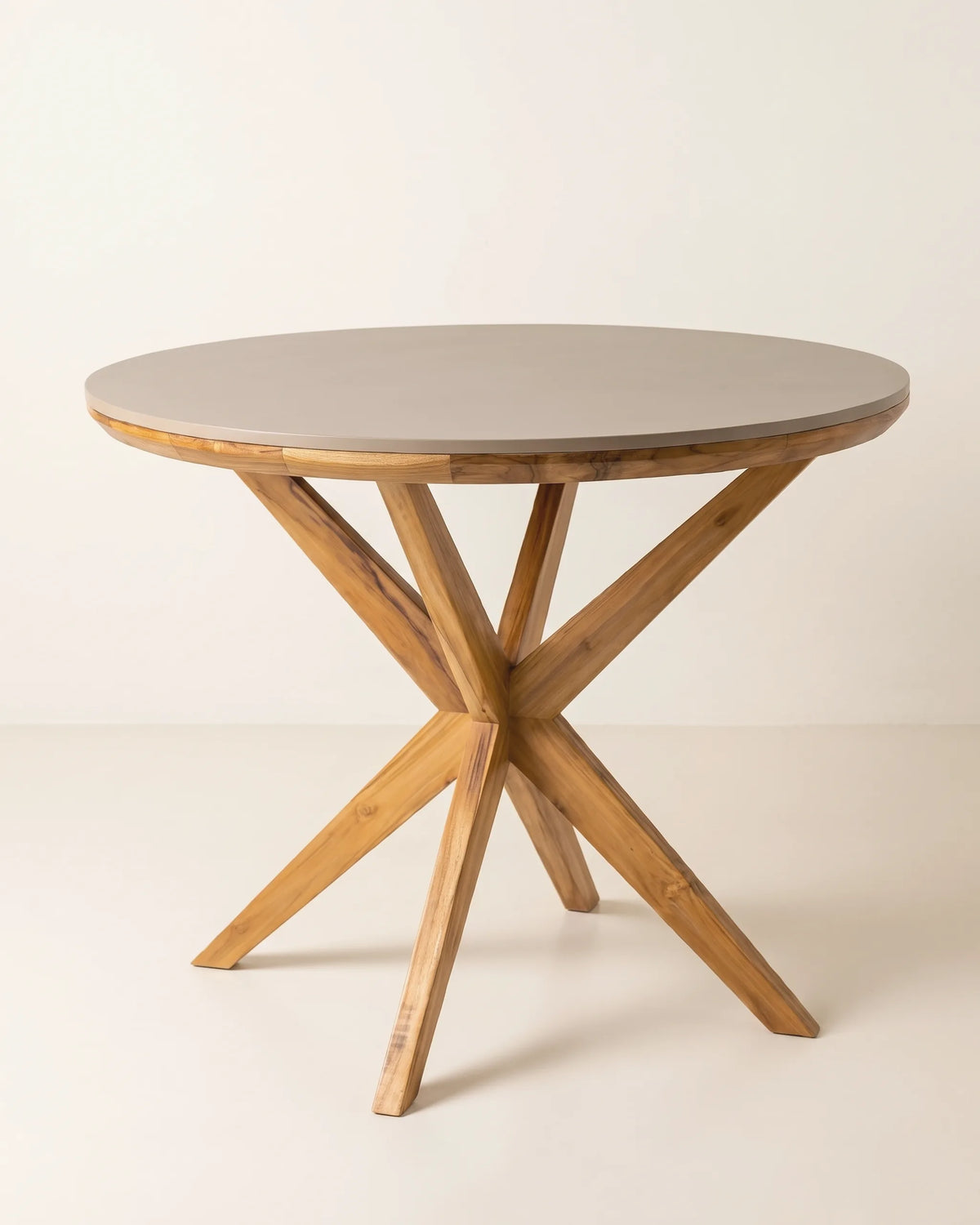 Mesa de comedor redonda con tablero taupé, aro de teca y base de patas cruzadas sobre fondo claro