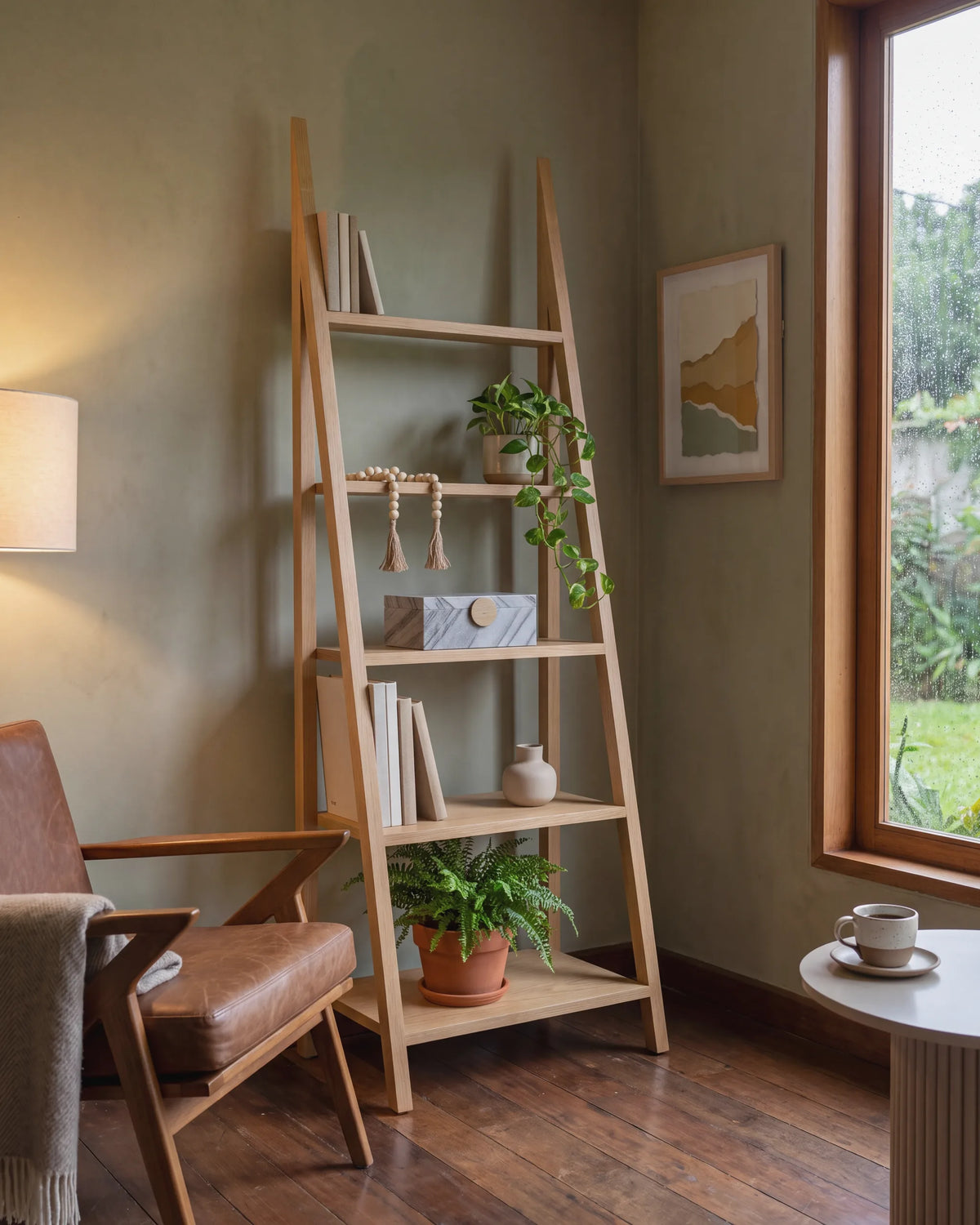 Repisa tipo escalera de roble con libros y plantas en una sala de lectura de Prado Centro