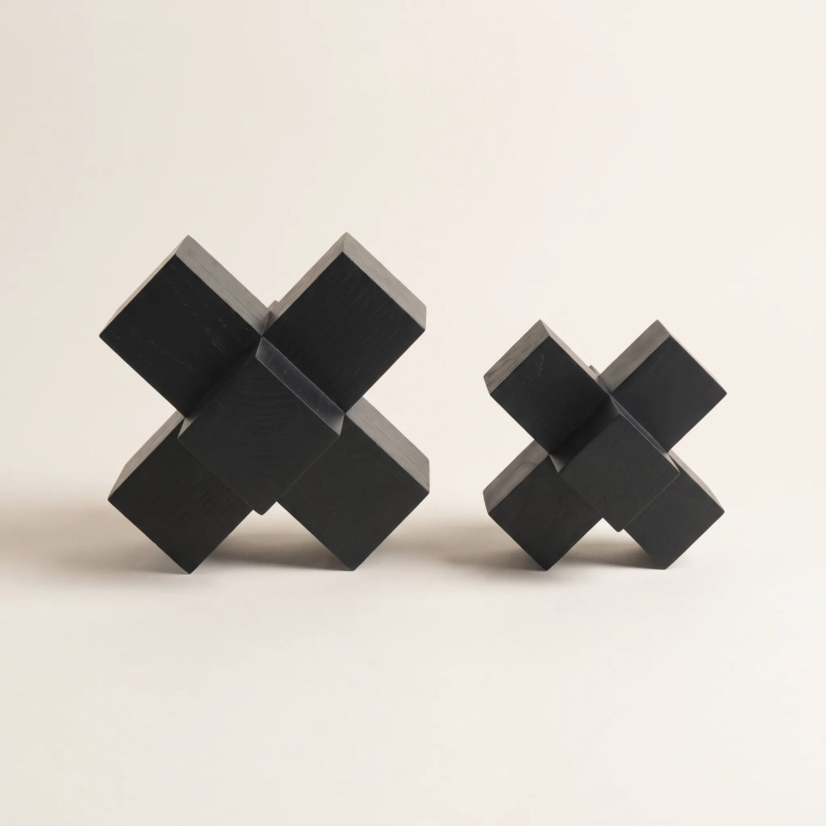Dos minas decorativas de madera en forma de cruz tridimensional en negro mate sobre fondo claro